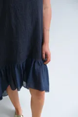 Vestido azul marino de lino italiano, sin mangas, con escote redondo y ruedo irregular con volados.