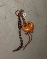 Llavero de calidad con diseño de pretzel marrón, ideal para decorar bolsos y carteras.
