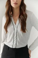 Remera blanca de mangas largas con escote en V y costuras decorativas en negro.