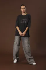 Remera negra de corte oversize con estampado abstracto en tonos rojos, grises y blancos.