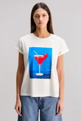 Remera negra de calce regular, confeccionada en jersey de algodón. Tiene cuello redondo, manga corta y estampado frontal de un trago con cereza sobre un fondo azul.