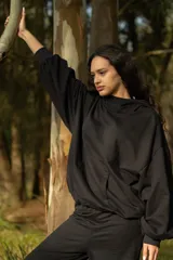 Conjunto deportivo negro compuesto por un hoodie con capucha y bolsillo canguro, y un pantalón jogging con bolsillos laterales y cintura ajustable con cordón.