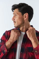 Sobrecamisa de algodón para hombre con interior de corderito, estampado a cuadros en tonos negro, blanco y azul. Tiene cierre de botones, bolsillos tipo cartera y logo en goma. El modelo usa talle M.