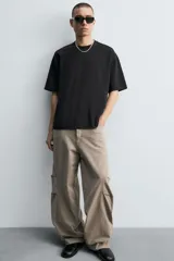 Pantalón de jean color marrón topo, de corte holgado y amplio en toda la pierna, con tiro medio, cinco bolsillos, efecto lavado, detalle de pinzas en perneras y cierre frontal con cremallera y botón.