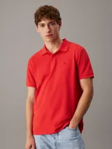 Chomba roja de piqué de algodón, corte regular, cuello clásico, cartera de botones, bajo con aberturas laterales y logo de Calvin Klein bordado en el pecho.