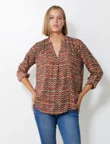 Blusa de gasa con estampado geométrico en tonos tierra (marrón, rojo, verde, amarillo). Presenta cuello solapa con escote en V y mangas largas ajustables con presilla y botón.