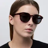 Lentes de sol redondos con montura carey y lentes negros polarizados. Fabricados con materiales bio-based G850 y patillas de propionato de celulosa. Protección UV400.