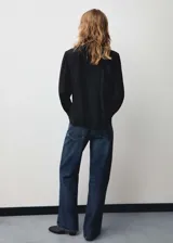 Blusa azul con lazo al cuello, de tejido fluido y satinado, con cierre oculto de botones y mangas largas abotonadas.