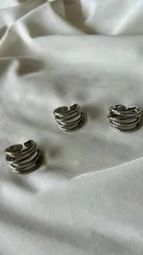 Anillo plateado de acero quirúrgico con diseño de múltiples aros finos.