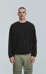 Sweater negro de corte holgado con cuello redondo y mangas largas con puños ajustados.