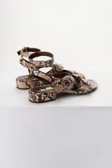 Sandalias bajas color marrón con estampado de piel de serpiente, tira delantera con detalle de hebillas y tira trasera con hebilla metálica.