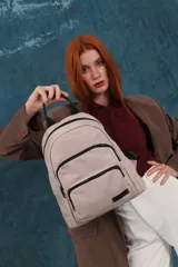 Mochila funcional color beige con detalles en negro, que incluye dos compartimentos con cierre y un bolsillo frontal para fácil acceso.