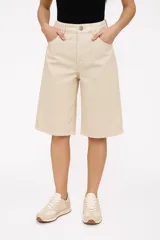 Bermuda de jean color beige, corte amplio y largo hasta la rodilla.