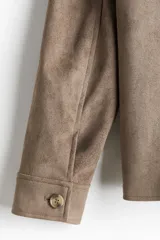 Campera marrón con cuello clásico y cierre frontal. Tiene bolsillos insertados al bies con botón a presión, bolsillo interior y botón en los puños. Corte estándar y forro interior.