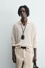 Sweater color crema de punto, con cuello polo y mangas largas. Tejido en hilatura de cáñamo con acabados en rib.