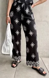 Pantalón negro con estampado de rombos blancos, de corte recto y tiro alto.