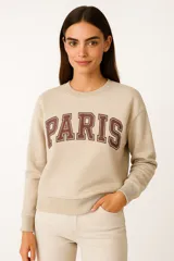 Buzo negro de cuello redondo y manga larga, con estampado frontal de la palabra "PARIS" en color lila con borde blanco.