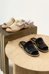 Sandalias de cuero negras con diseño de tiras cruzadas y detalle de elástico en el talón.