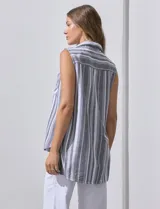 Blusa sin mangas con estampado a rayas verticales en tonos grises y blancos. Tiene cuello camisero, cierre frontal con botones y dos bolsillos con solapa en el pecho.