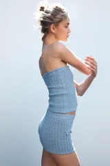 Shorts de tejido con textura color celeste, de tiro alto y cintura elástica. Presenta falsos bolsillos con solapa y botón metálico en el delantero.