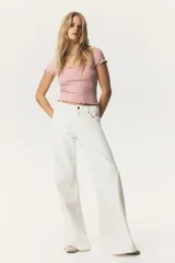 Top rosa de punto acanalado con escote redondo y mangas cortas. Tiene ribete de encaje en escote y mangas, y corte ajustado.