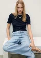 Pantalón de jean celeste de corte wide leg, tiro alto, cinco bolsillos, cierre con cremallera y botón, trabillas para cinturón y bajo deshilachado.