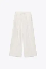 Pantalón blanco de lino, de corte ancho, tiro medio, con trabillas y cintura elástica ajustable con cordones.
