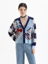 Cardigan oversize de punto jacquard multicolor con predominancia de celeste y azul marino. Cuenta con cuello en V, cierre frontal de botones y un diseño artístico que incluye bordados de cerezas y flores. Las mangas largas presentan un patrón de franjas horizontales.