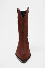 Botín de mujer estilo cowboy color marrón de serraje con puntera fina y tiradores laterales. Tacón de 5 cm.