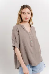 Camisa color topo confeccionada en lino, de corte holgado, con escote en V abotonado, bolsillo frontal y mangas 3/4 arremangables.