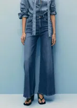 Pantalón de jean azul de tiro alto, corte wide leg, con bolsillos delanteros y traseros, cierre con cremallera y botón.