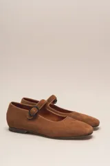 Zapato estilo Mary Jane color marrón, de cuero, con punta redondeada y tira sobre el empeine con hebilla.