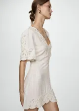 Vestido corto color crudo con bordados florales, escote en V y mangas cortas con detalle de calado.