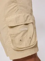 Bermuda color beige de corte recto con bolsillos cargo laterales y cintura elastizada con cordón ajustable.