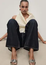 Pantalón de jean azul oscuro, corte wide leg, tiro bajo, con cinco bolsillos y cierre frontal con cremallera y botón.