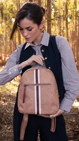 Mochila color beige con diseño capitoneado, bolsillo frontal con cierre, asa de mano y correas regulables.