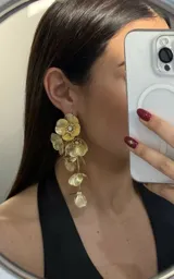 Par de caravanas colgantes doradas con forma de flores y detalles de strass.