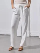 Pantalón de lino a rayas verticales color beige y blanco, con pretina ancha elastizada, lazo de ajuste y bolsillos inclinados.