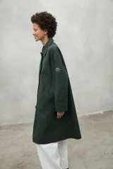 Chaqueta color beige, repelente al agua, con cuello clásico, cierre con botones, bolsillos laterales y corte holgado. Fabricada con poliéster reciclado y algodón orgánico.