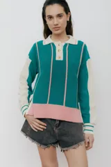 Polo de punto con rayas verticales en verde esmeralda y rosa, mangas largas color crema con puños acanalados, cuello clásico y cierre parcial con botones.