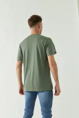 Remera verde militar de manga corta con estampa fotográfica en blanco y negro de un edificio y texto con la dirección de la marca.