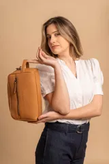 Neceser color tostado de símil cuero, con doble compartimento superior con cierre y bolsillo frontal con cierre. Tiene asa lateral para fácil transporte.