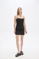 Vestido corto de algodón color negro, con breteles finos y detalle de broderie en la parte superior del pecho. Presenta un diseño entallado con cuello redondo y cierre.