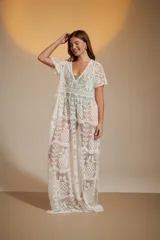 Vestido largo blanco de encaje con diseño de piñas bordadas. Presenta escote en V profundo y mangas cortas holgadas.