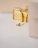 Collar asimétrico dorado con cadena de bolitas y dije esférico.