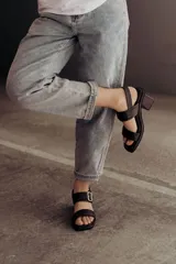 Sandalia de cuero color negro con taco bloque medio y punta cuadrada. Presenta dos tiras anchas sobre el empeine, una de ellas con hebilla metálica dorada, y una tira de sujeción en el talón. Posee base acolchonada para mayor comodidad.