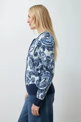 Chaqueta tejida color verde agua con estampado floral en azul marino, de corte recto y cuello redondo.