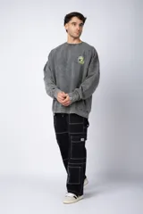 Buzo de cuello redondo y corte oversize en tela friza, color gris con efecto acid wash. Presenta un estampado frontal en color verde lima con un diseño abstracto.