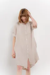 Vestido camisero corto color verde oliva, confeccionado en lino 100%. Tiene botones en la parte delantera, cuello camisero, mangas cortas con botón para arremangar y bolsillos laterales.