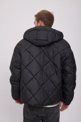 Campera puffer negra con capucha ajustable con cordón, cierre con cremallera, bolsillos frontales y tejido acolchado resistente al viento.